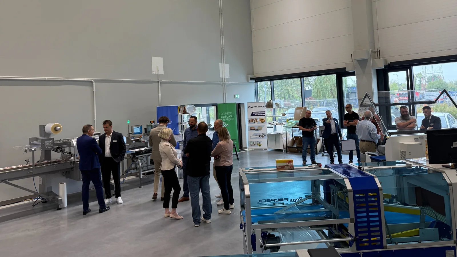 Visitors discussing packaging machinery in the POLPACK ZEUS showroom.