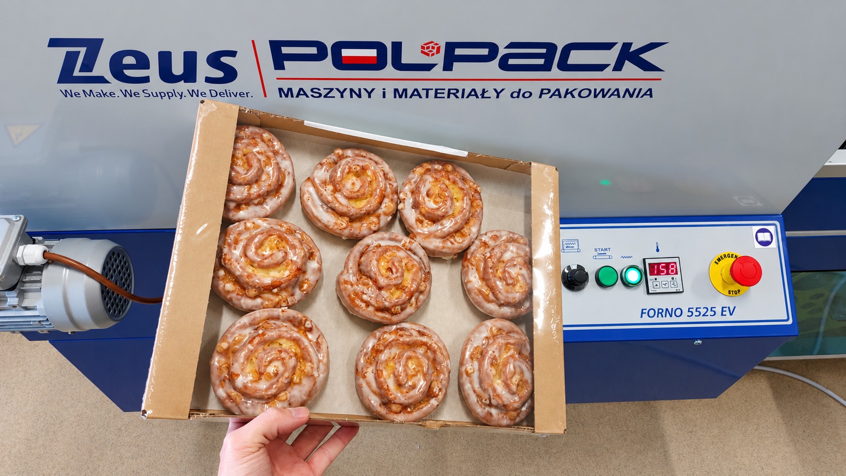 Sweet pastries in a film-wrapped carton beside a shrink tunnel